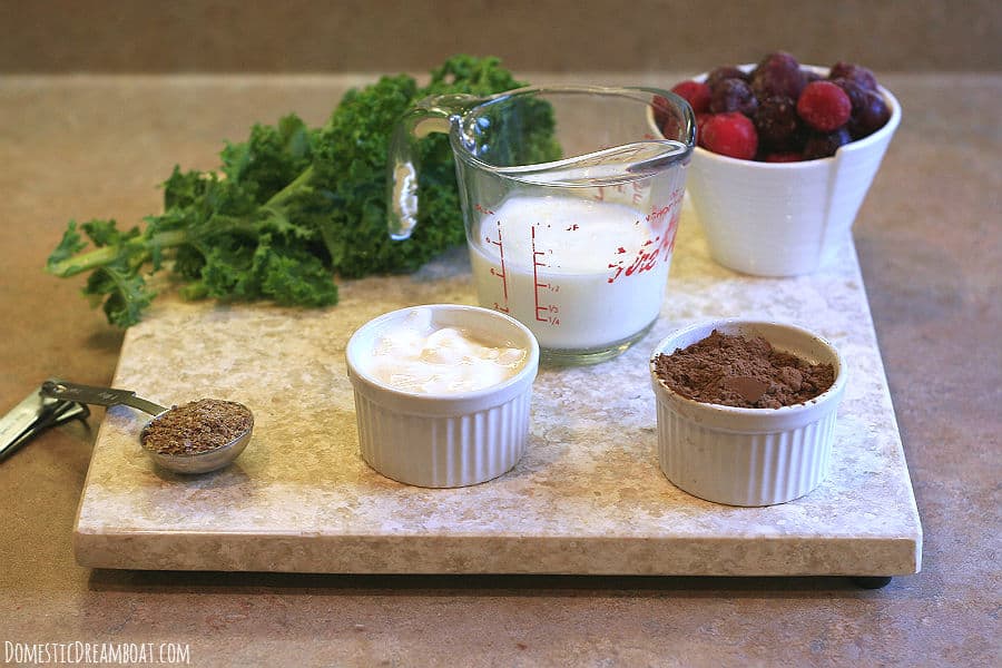 Ingredients for a chocolate cherry smoothie: kale, kefir, cherries, cocoa, Greek yogurt, ground flaxseed