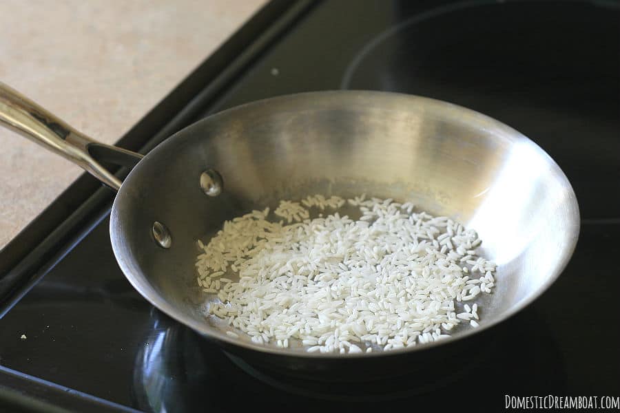 White rice roasting in a dry, stainless steel skillet.