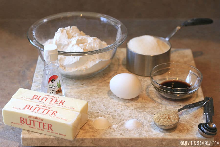 Ingredients to make sugar cookies: flour, sugar, egg, vanilla, almond extract, butter, baking powder, and salt.