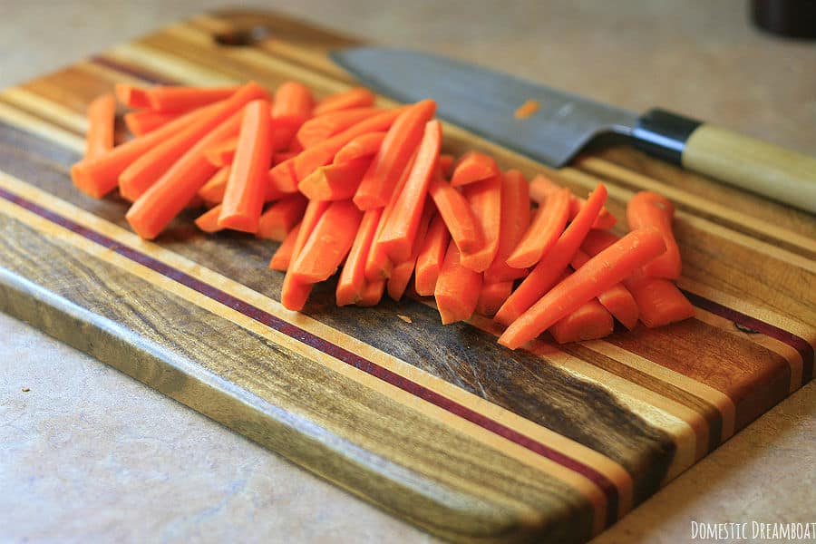 Peeled and cut carrots on a wood cutting board.