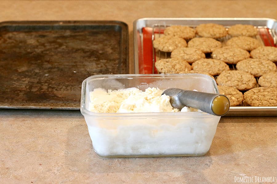 A tray of homemade oatmeal cookies and a glass container of homemade vanilla ice cream.