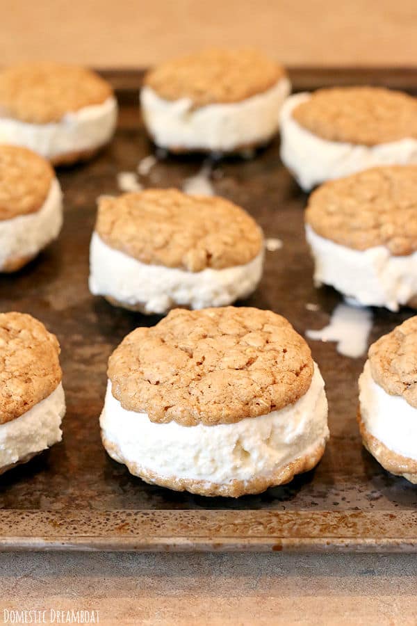 Ice cream sandwiches made with oatmeal cookies on a baking sheet.
