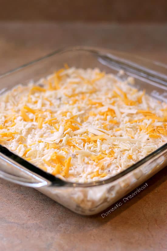 Unbaked cheesy hashbrown casserole in a glass baking dish.