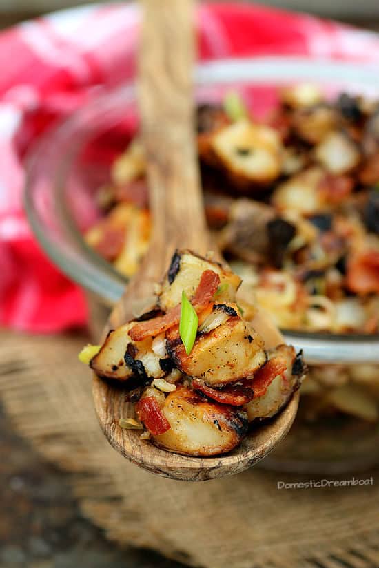 A wooden spoon full of grilled potato salad.