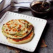 Two whole Green Onion Cakes on a square, white plate.