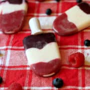Red, white, and blue striped berry popsicles on a red and white plaid background