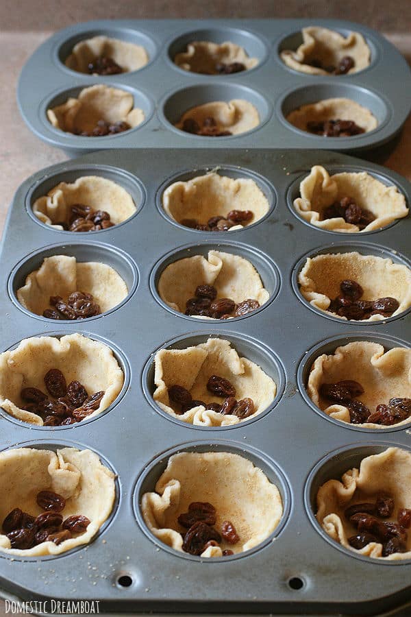 Pastry dough and raisins in muffin tins