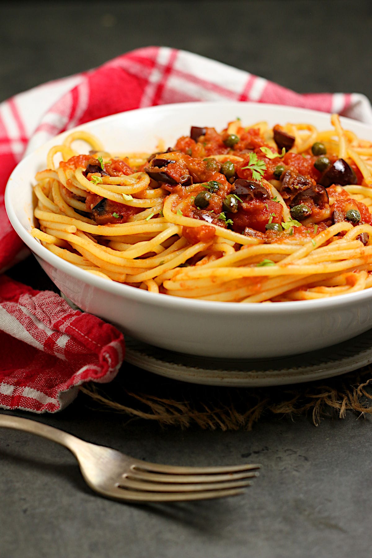 Spaghetti Puttanesca in a white bowl.