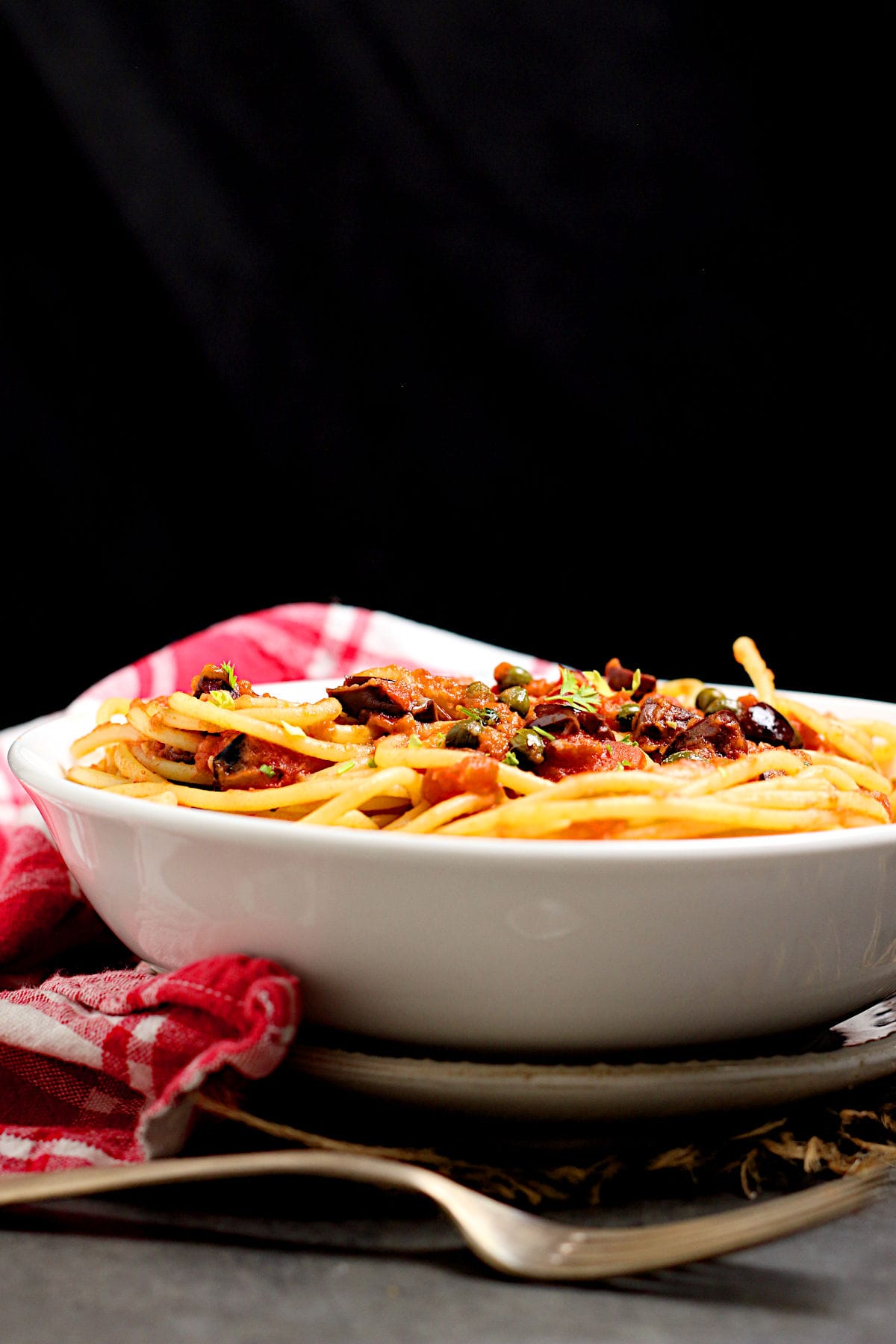 Spaghetti Puttanesca in a white bowl.