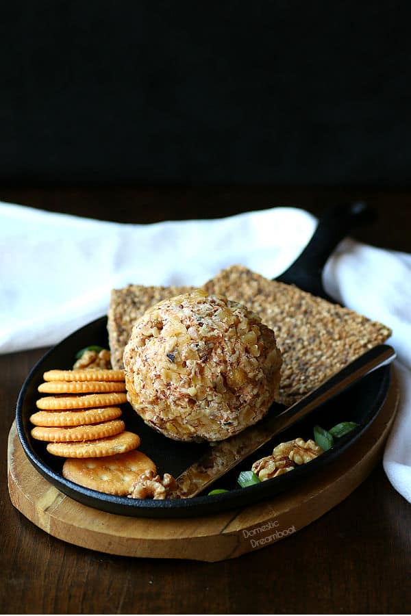 A homemade cheese ball with crackers on a serving platter.