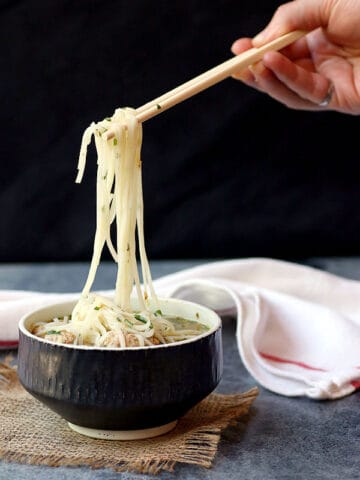 Lifting noodles out of a bowl of noodle soup with chopsticks