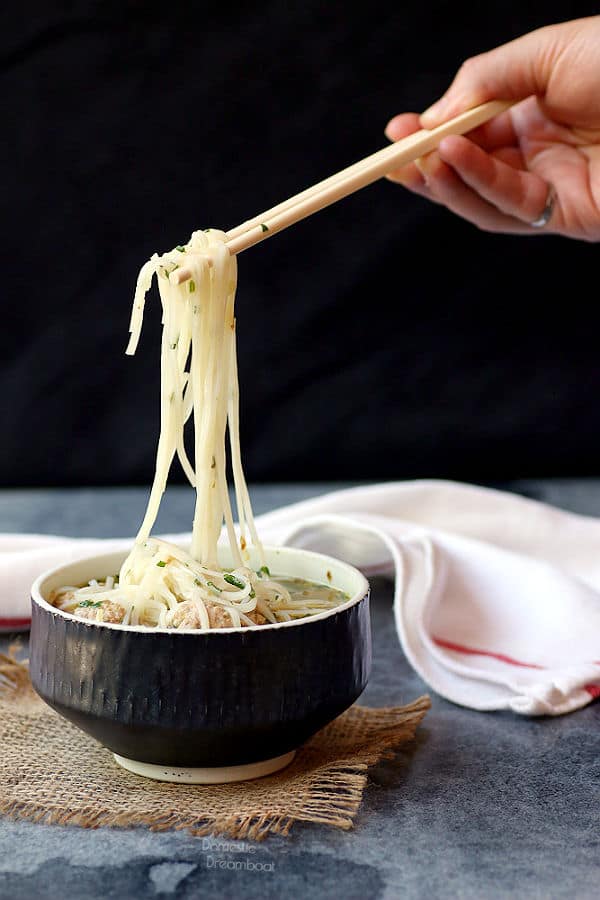 Lifting noodles out of a bowl of noodle soup with chopsticks
