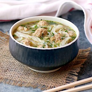 A bowl of rice noodle soup with turkey meatballs