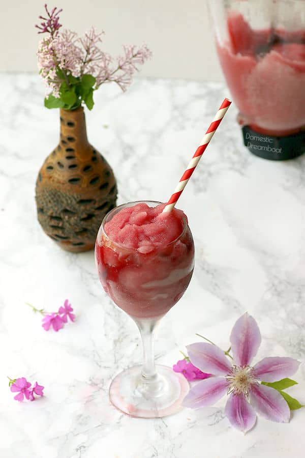 Frozen wine slushie in wine glass surrounded by flowers
