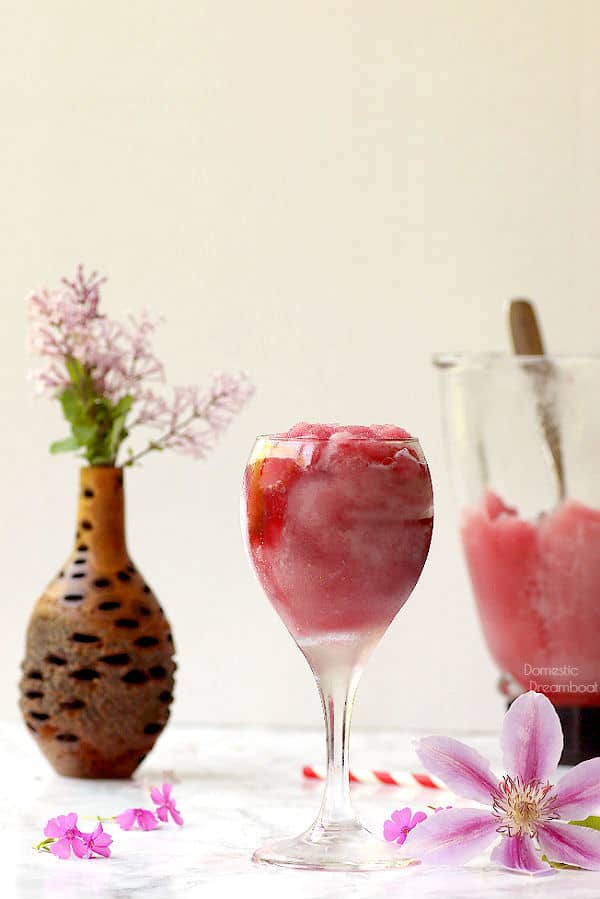 Frozen wine slushie in wine glass surrounded by flowers