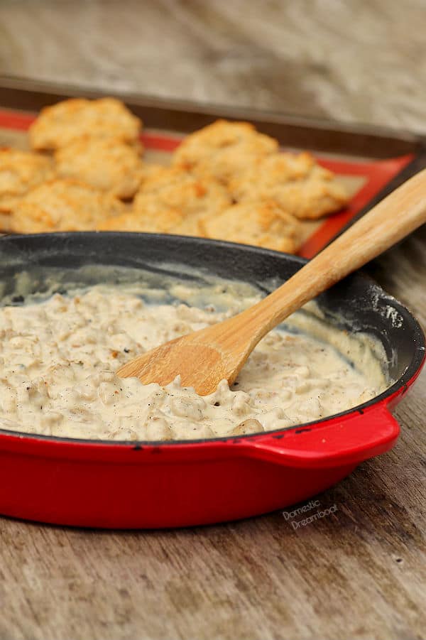 Sausage Gravy in skillet with biscuits in the background