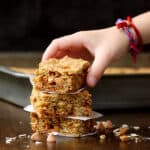 A stack of butterscotch oatmeal bar with a child's hand grabbing one.