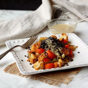 Roasted Vegetables and black lentils on a plate with tahini dressing