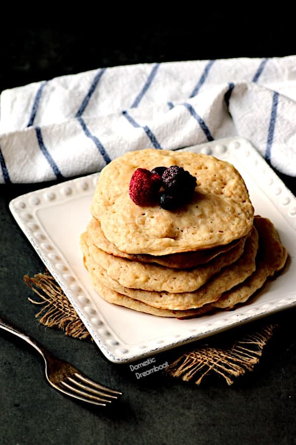 A stack of crumpet pancakes with berries on top.
