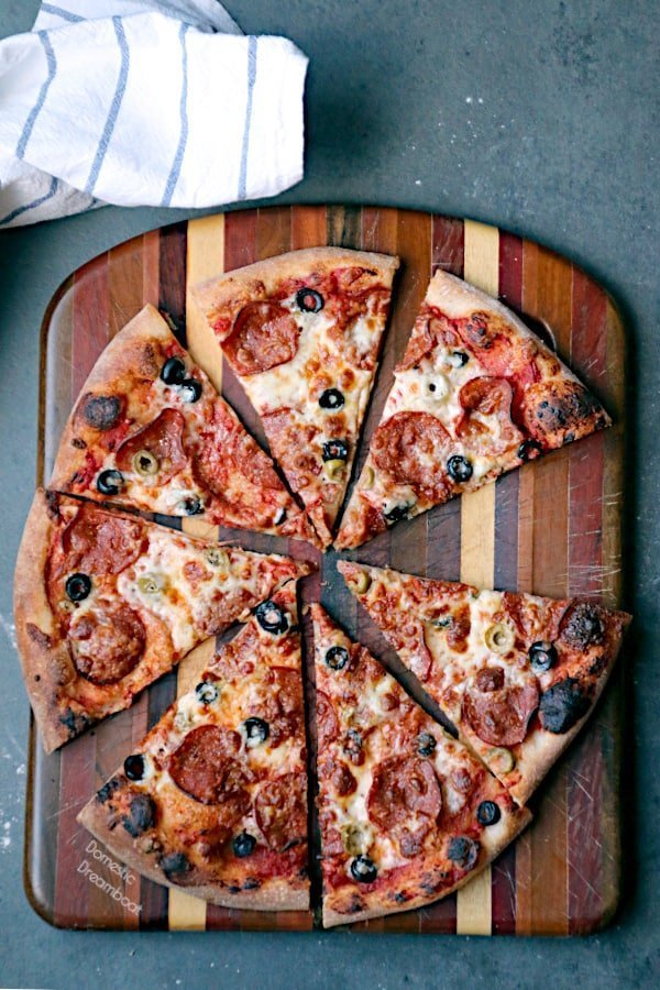 A sliced homemade pizza with pepperoni and olives.