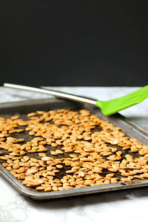 Homemade roasted pumpkin seeds on a baking sheet.