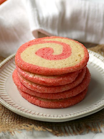 A stack of candy cane swirl cookies on a white plate.