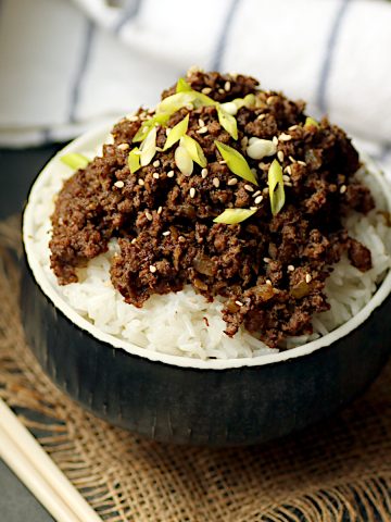 Korean beef and mushrooms over rice in a black bowl.