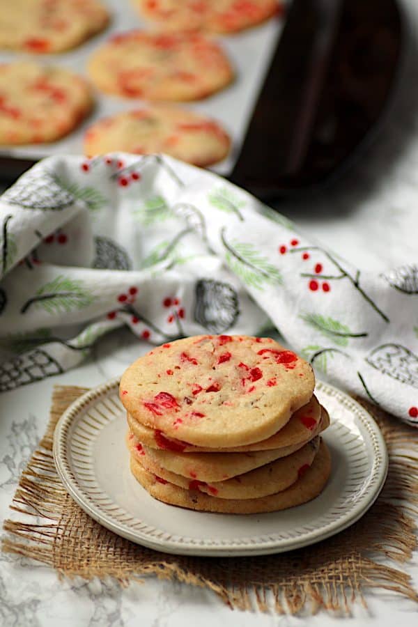 A stack of cherry pecan icebox cookies on a white plate.