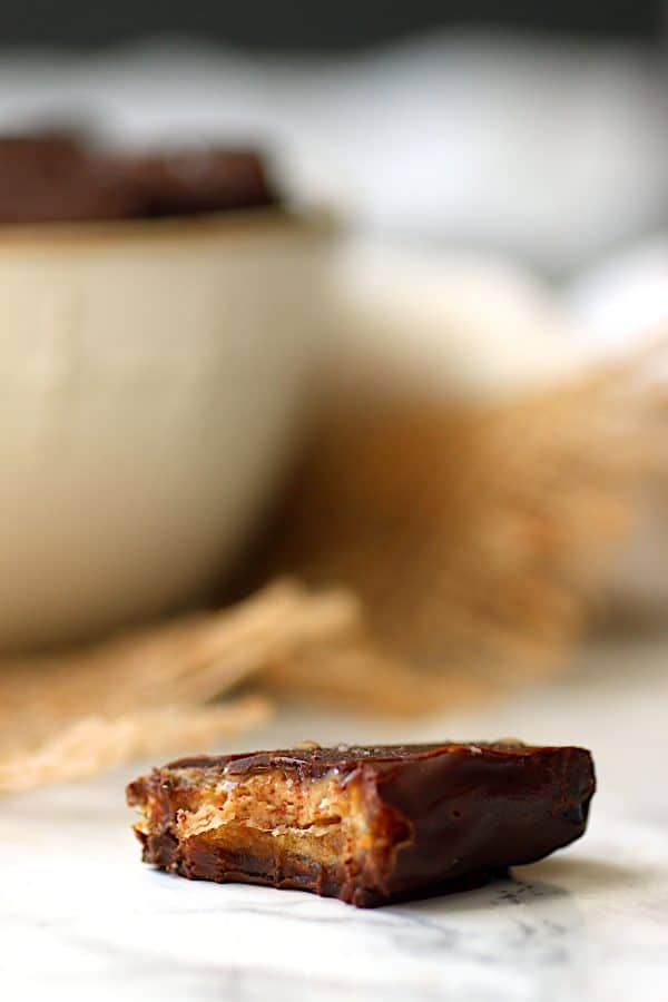 Closeup photo of a chocolate covered date stuffed with almond butter.