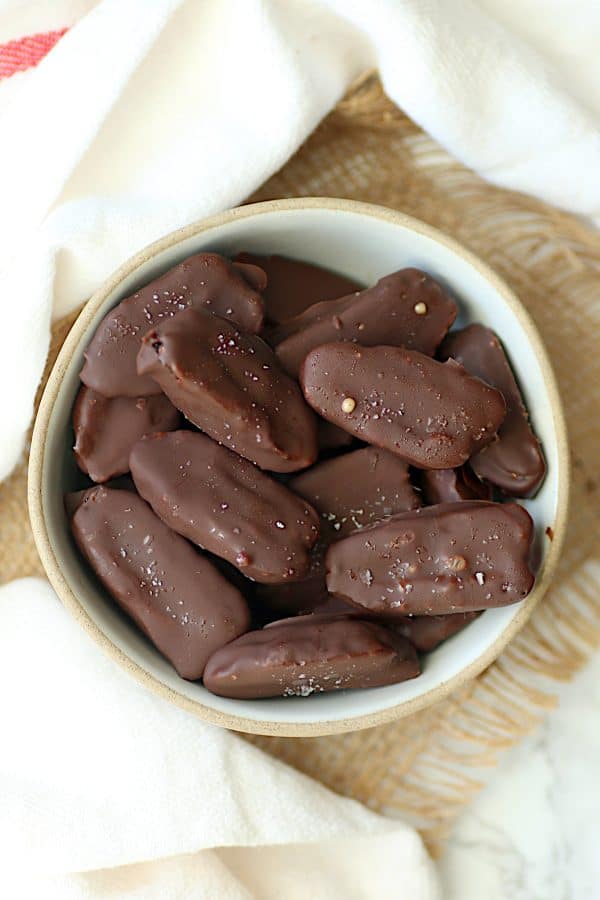 Overhead photo of chocolate covered dates in a white bowl.