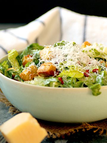 Caesar salad with shredded Parmesan cheese in a pale blue bowl.