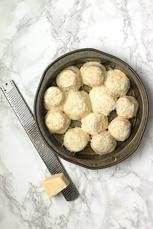 Uncooked pizza rolls in a round baking pan.