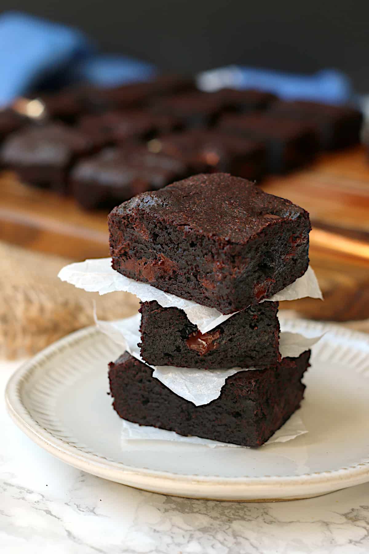 A stack of fudgy brownies on a white plate.