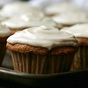A closeup photo of a carrot cake cupcake with cream cheese frosting.