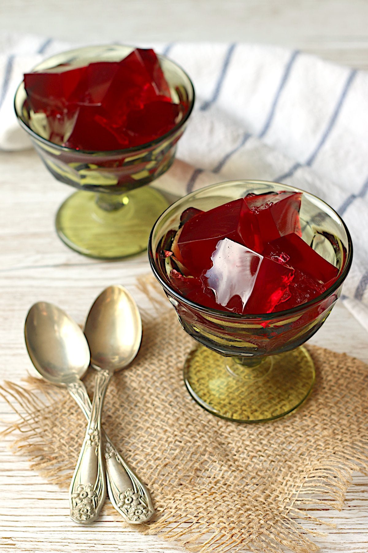 Two servings of red homemade jello in green dessert goblets.