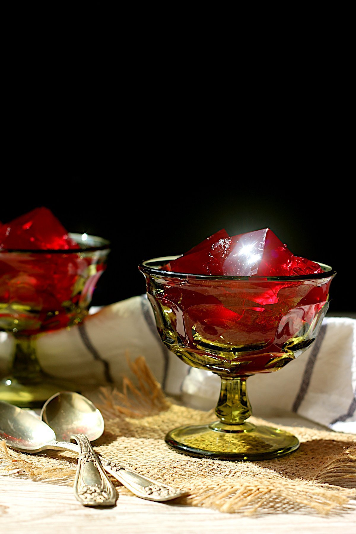 Red homemade jello in a green dessert goblet.