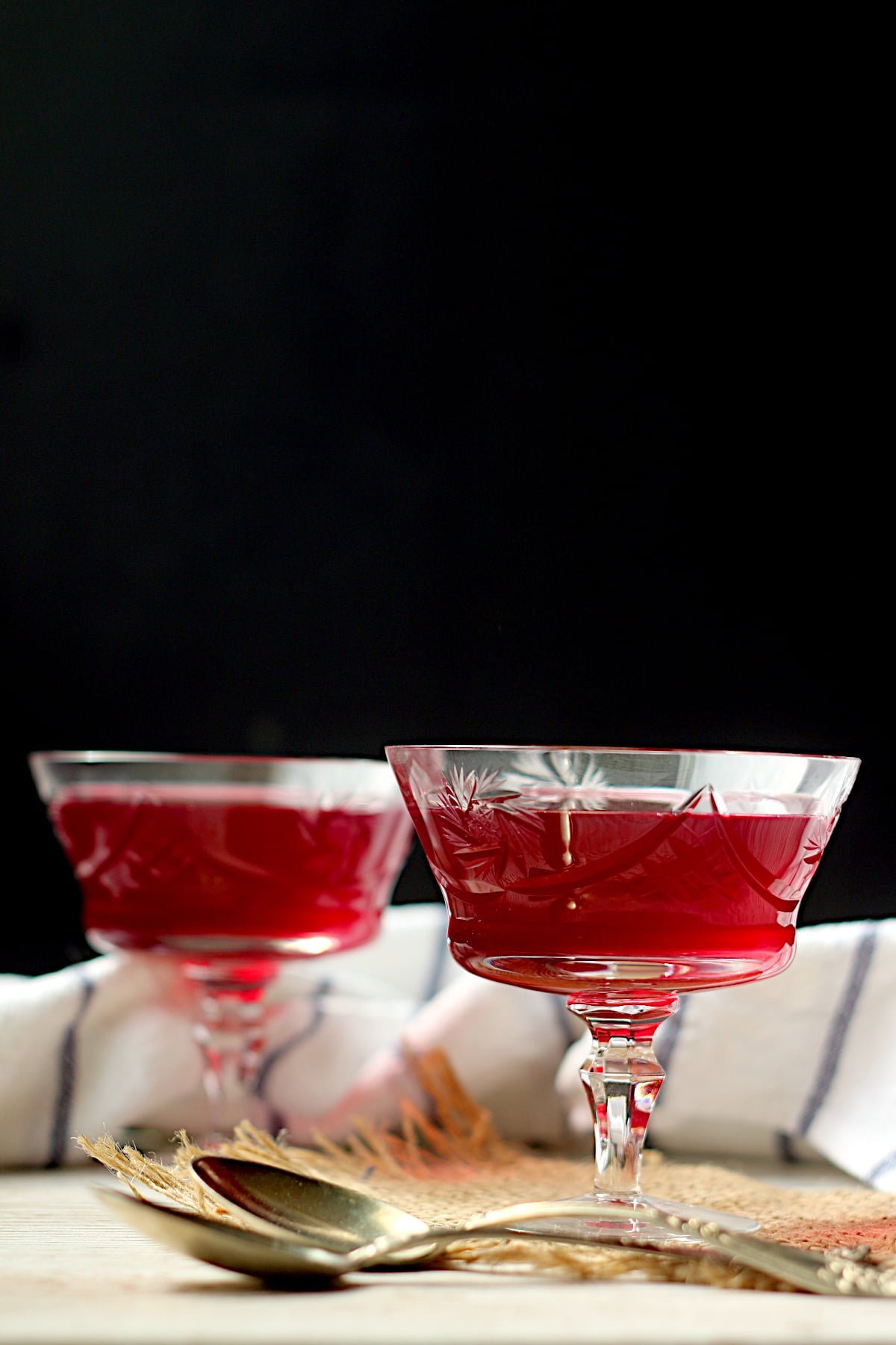 Two servings of red homemade jello in crystal glasses.