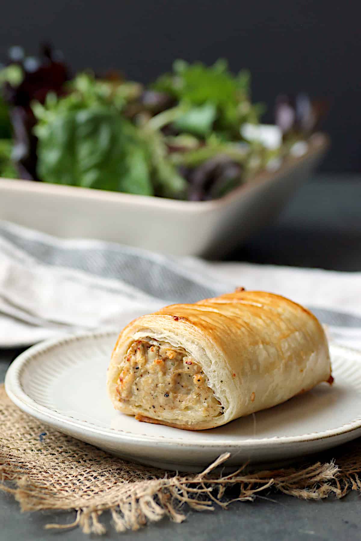 A singer larger snack-sized sausage roll on a white plate.