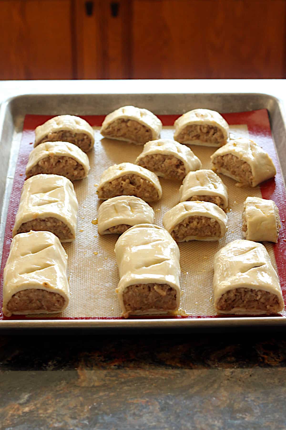 Unbaked sausage rolls on a baking sheet.