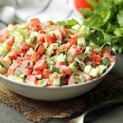 Tomato and cucumber salad in a white bowl.