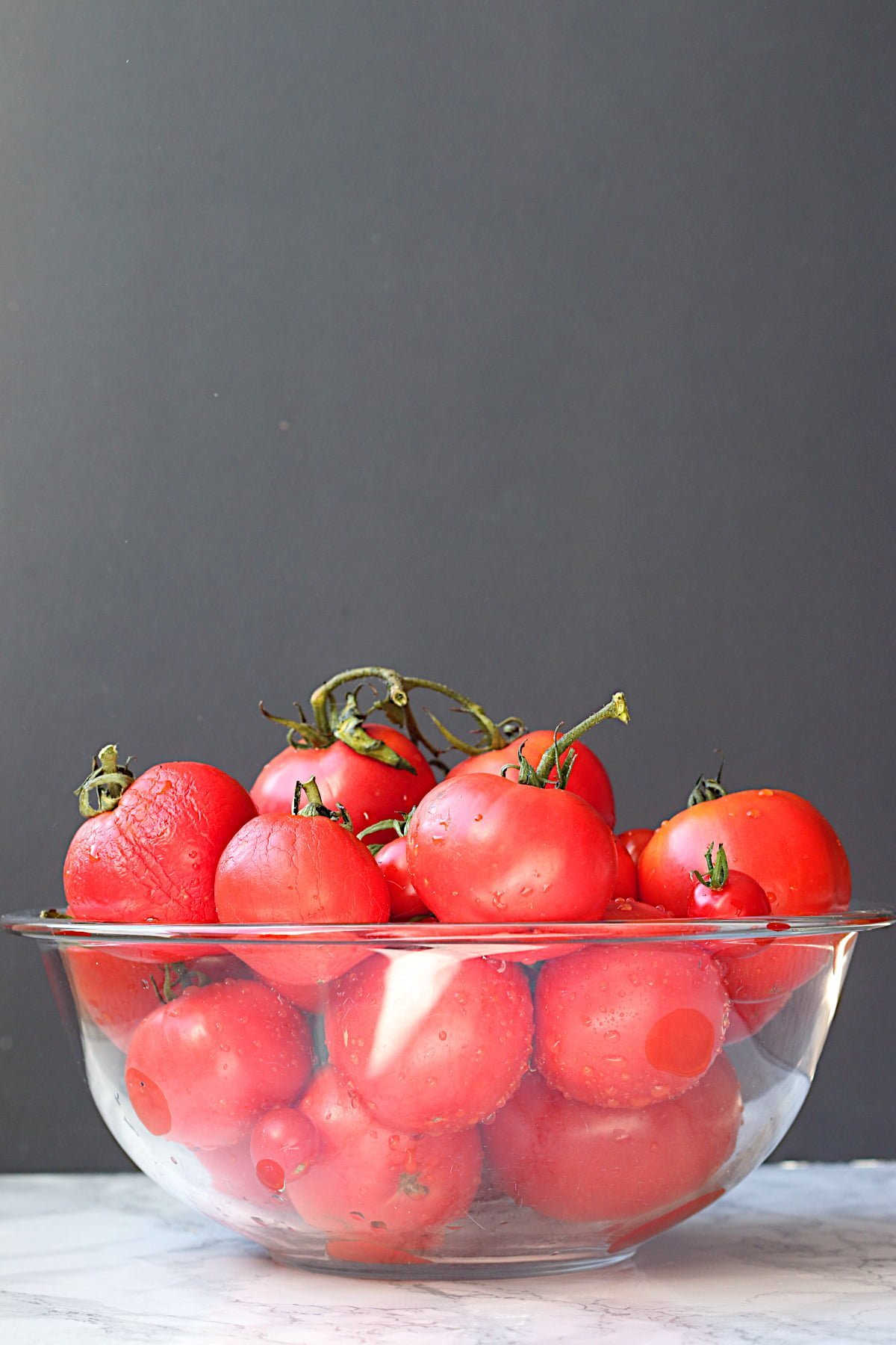 Fresh, ripe tomatoes in a glass bowl.
