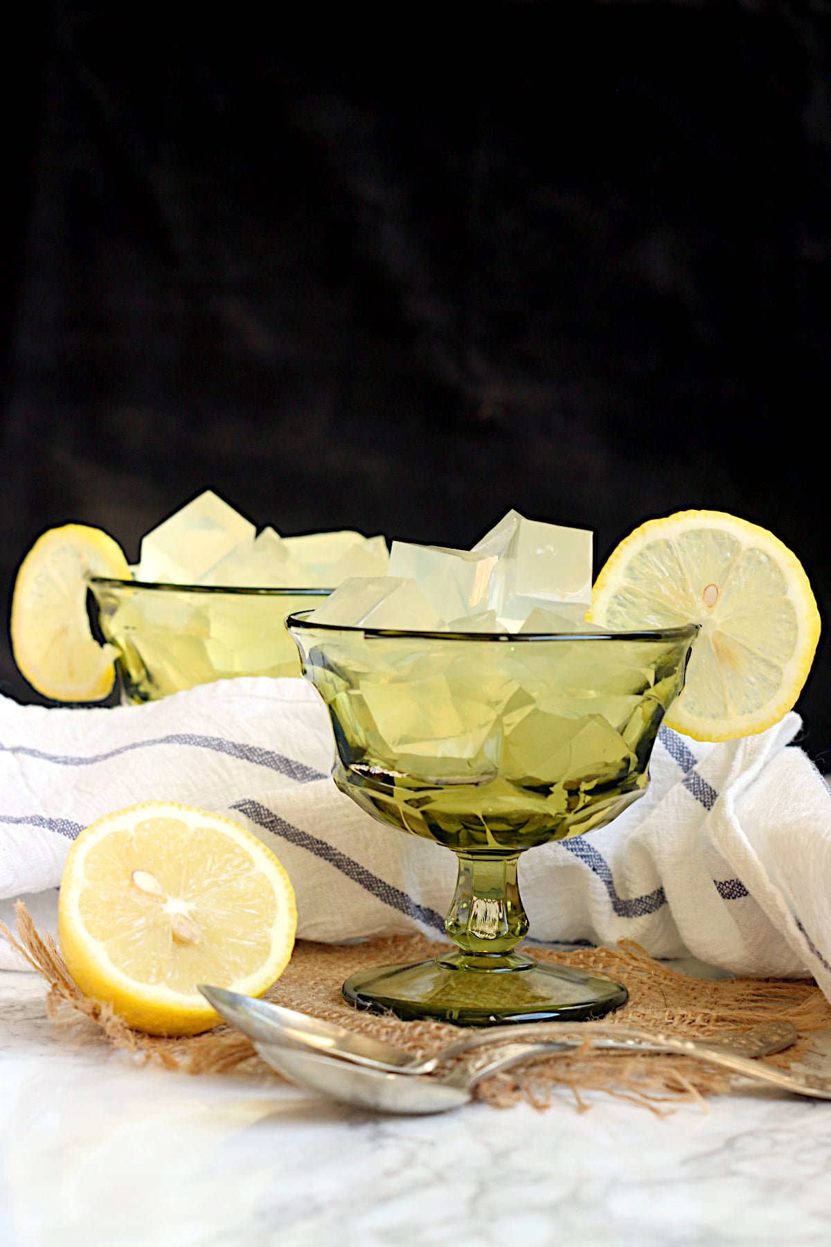 DIY Lemon Jello cut into cubes in a green dessert goblet.