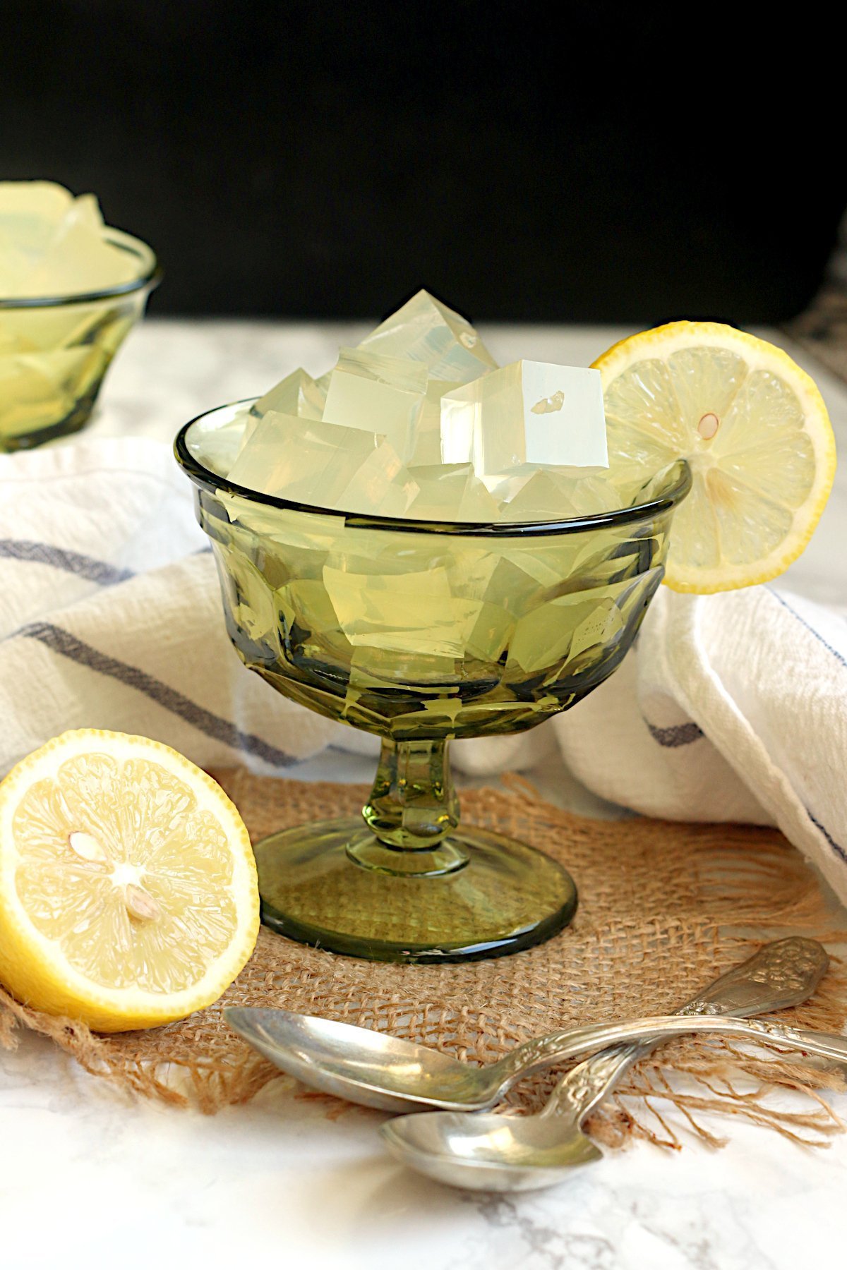 DIY Lemon Jello cut into cubes in a green dessert goblet.