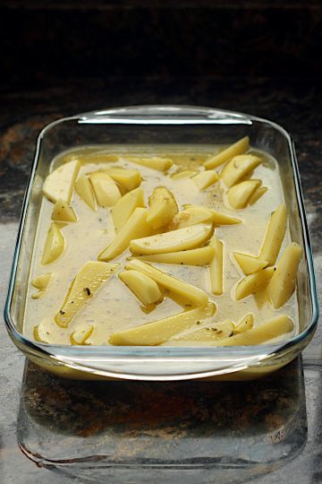 Greek lemon potatoes in a glass baking dish before cooking.