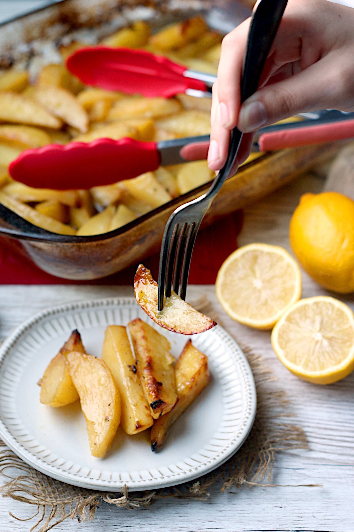 A fork picking up a Greek Lemon Potato from a small white plate.