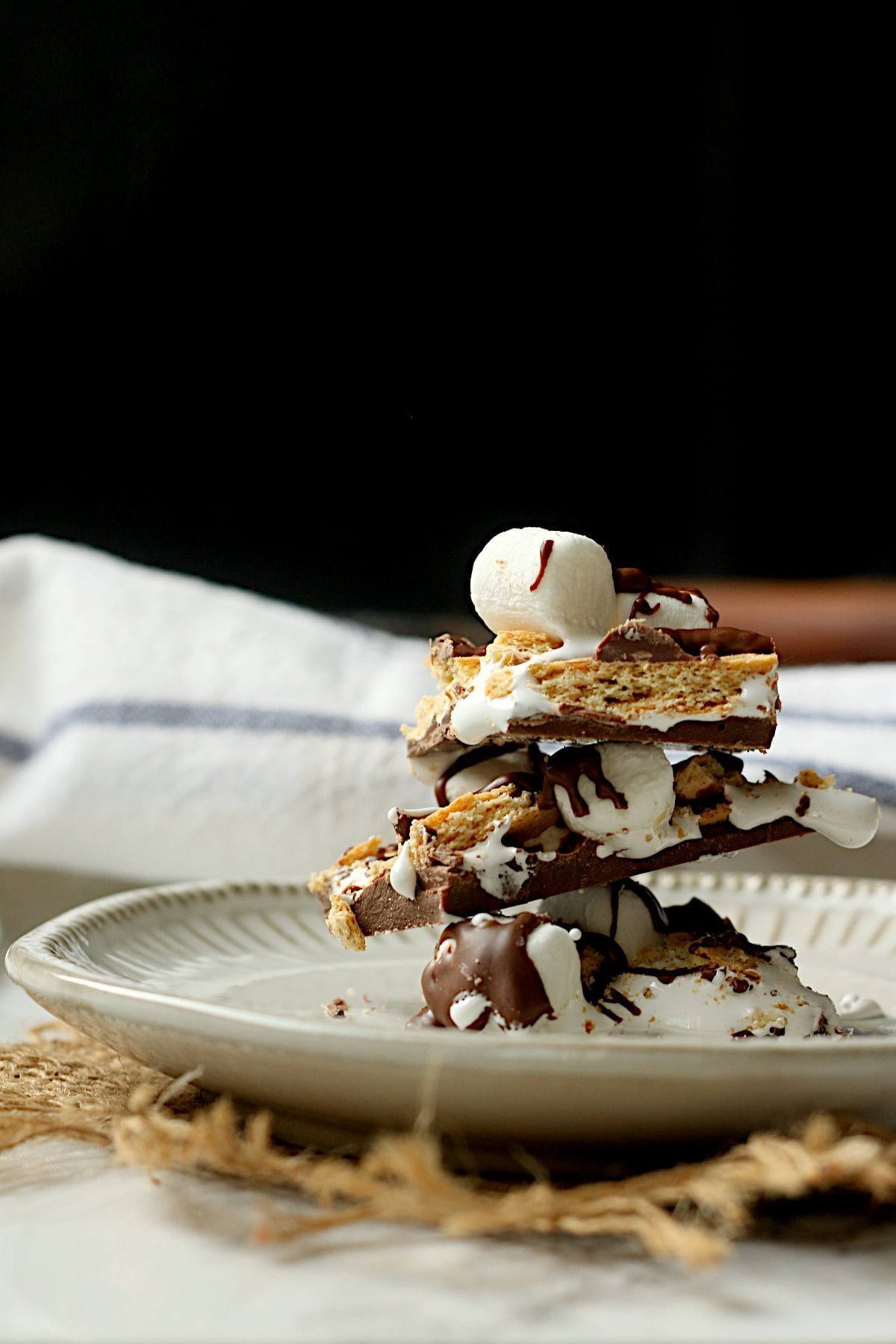 A stack of pieces of smores bark on a white plate.