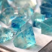 A closeup photo of blue Japanese Crystal Candy on a parchment-lined baking sheet.