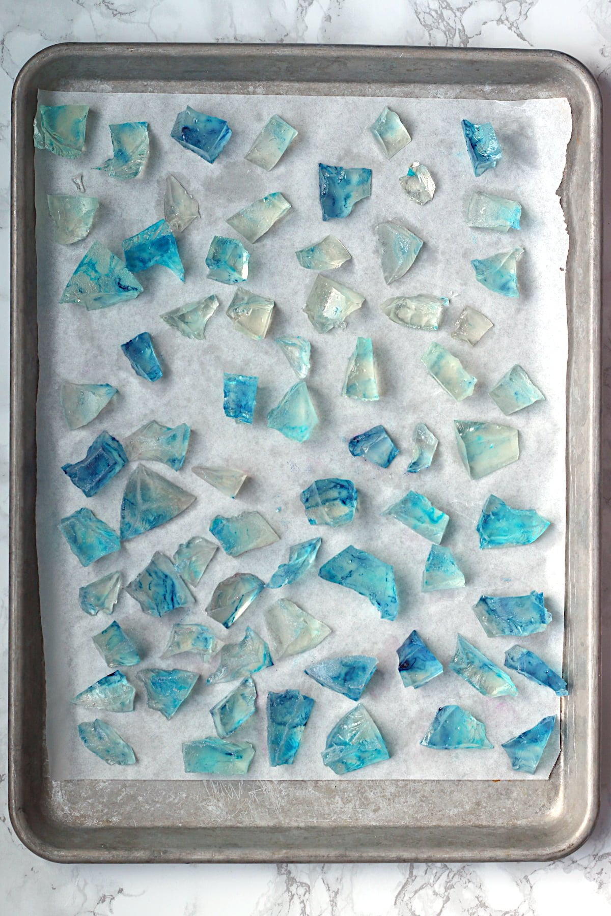 Overhead photo of blue Japanese crystal candy on a parchment-lined baking sheet.
