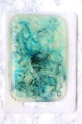 A slab of blue marbled jelly on a cutting board.