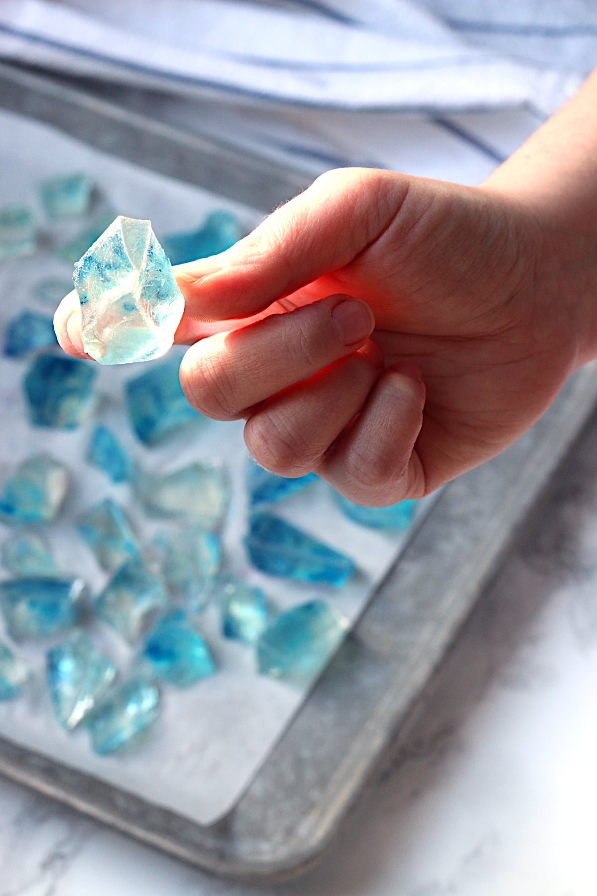 A hand holding a piece of blue Japanese Crystal Candy.
